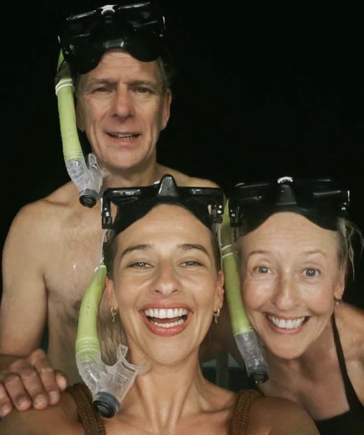 Three people, a man and two women, wearing snorkeling masks on their foreheads with snorkels attached, smiling.