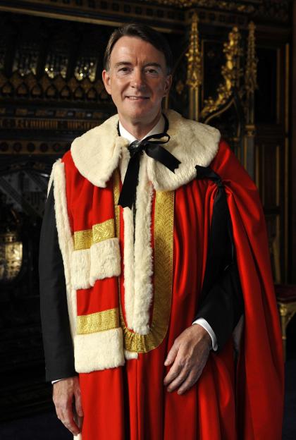 Lord Mandelson dressed in red robes with white fur trim and gold detailing.