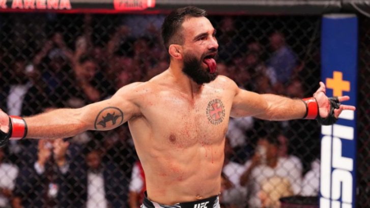 Mixed martial arts fighter sticking out his tongue and raising his arms in celebration.