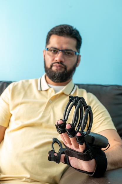 Raza Aslam wearing a device that exercises his damaged hand after being paralyzed.