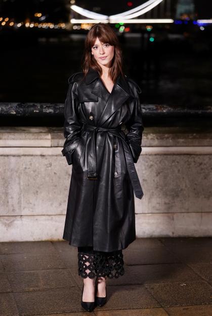 Daisy Edgar-Jones in a black leather trench coat and black heels.