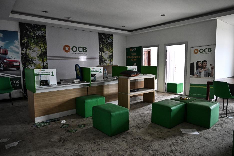 An abandoned or disheveled OCB bank branch with green seating and promotional posters.