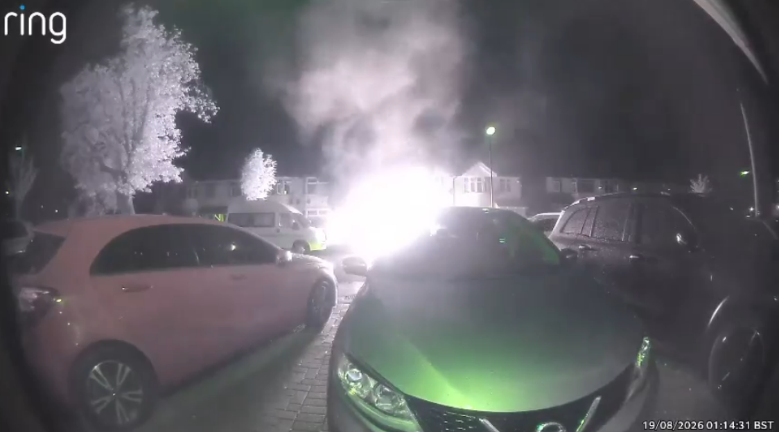 A home engulfed in flames, captured by a Ring doorbell camera at night.