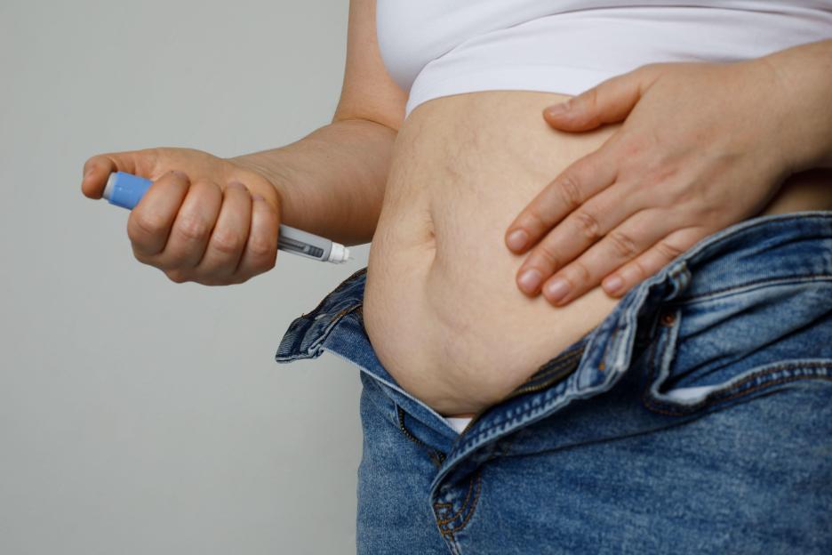 Woman taking an insulin or semaglutide shot in her stomach at home.