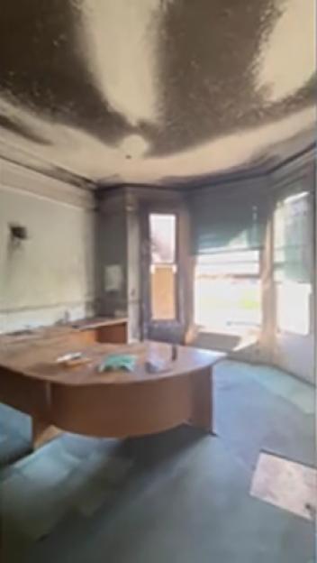 Interior of a fire-damaged office with soot-covered walls and ceiling.