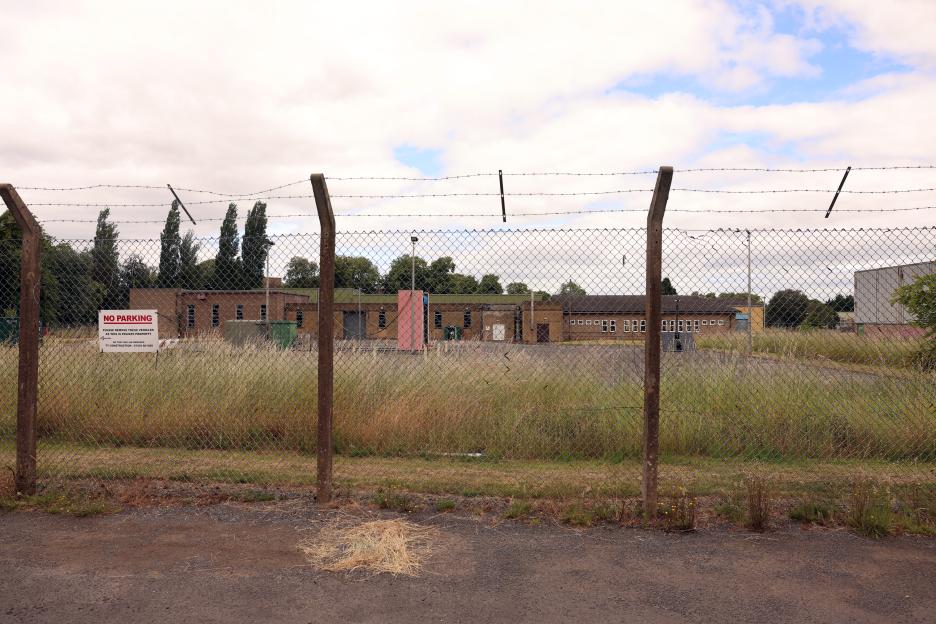 A fenced-off area of buildings at RAF Linton on Ouse, with a "NO PARKING" sign visible.