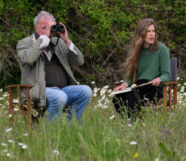Jeremy Clarkson using binoculars while Hannah Bourne-Taylor writes in a field.