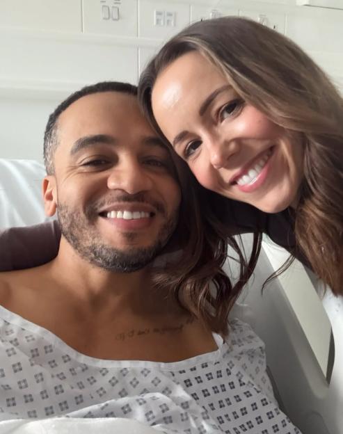 JLS star Marvin Humes in a hospital gown with Rochelle Humes leaning on him.