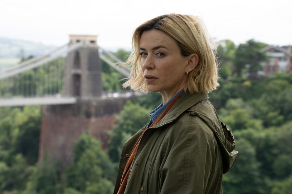 Eve Myles as Detective Annie Cassidy in a khaki jacket, with a bridge in the background.