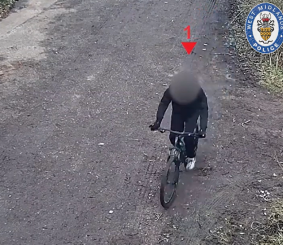 Overhead view of a person on a bicycle on a dirt path with a West Midlands Police logo and red arrow pointing forward.