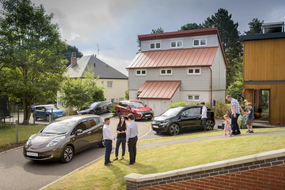People and children in a neighborhood with electric cars.