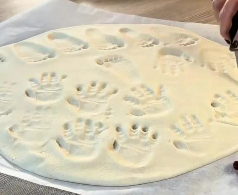 Salt dough hand and foot impressions on parchment paper.