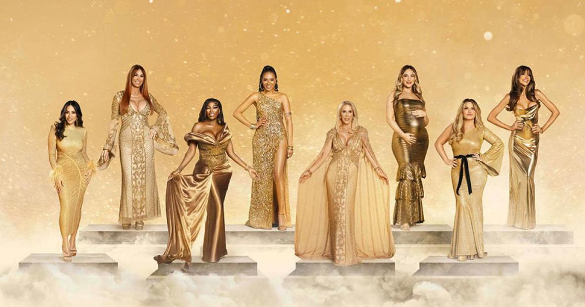 The Real Housewives of Cheshire cast, including Seema Malhotra, Lauren Simon, Lystra Adams, Sheena Lynch, Rachel Lugo, Paige Chohan, Nicole Sealey, and Ell Egar, posing in golden gowns on tiered platforms.