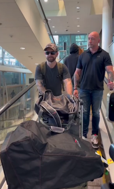 Two men and luggage on an escalator in an airport.
