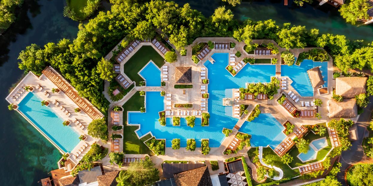 Aerial view of the Fairmont Mayakoba luxury hotel with multiple pools and lush greenery.