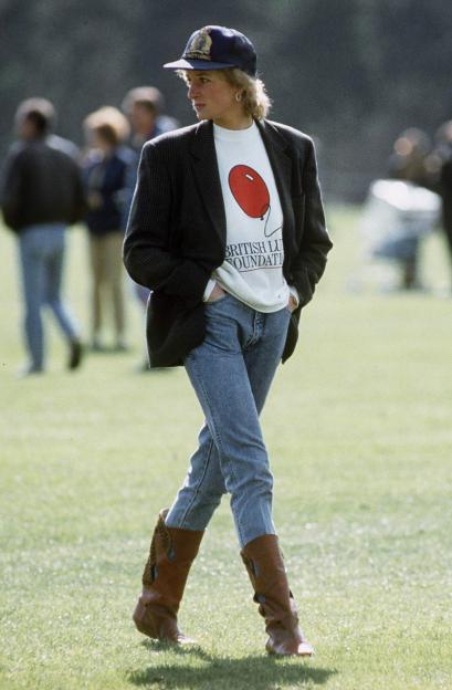 Princess Diana walking at Guards Polo Club, wearing a British Lung Foundation sweatshirt, jeans, boots, and a baseball cap.