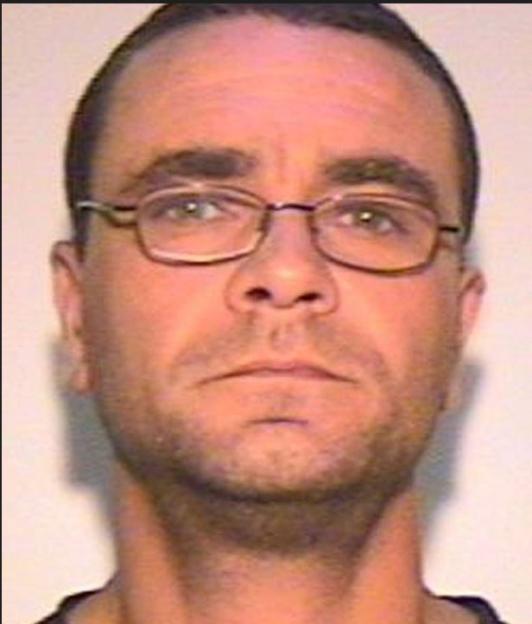 Mugshot of Andrew Malkinson, with short dark hair, glasses, and a scruffy beard.