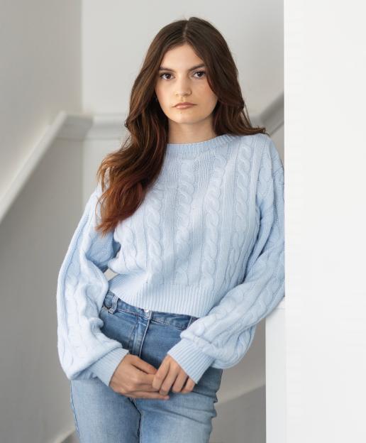 Kadie Don in a light blue cable knit sweater and jeans.