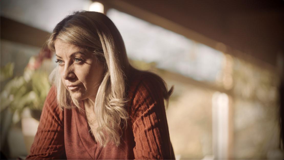 A woman with blonde hair and blue eyes looking thoughtful.