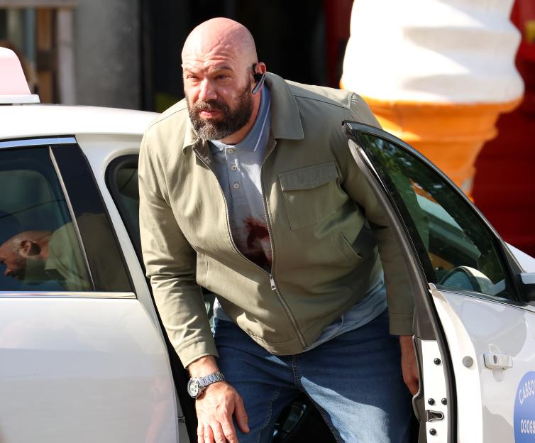 Tom Davis, with a bloodstained shirt, gets out of a white car.