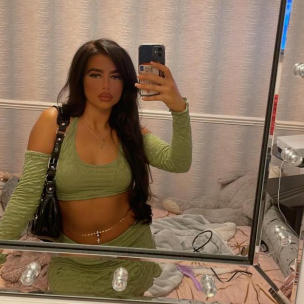 A young woman, Darcy Ross, takes a selfie in a mirror.