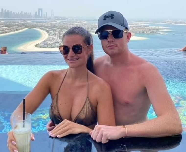 Couple relaxing in infinity pool overlooking city skyline.