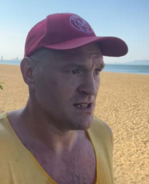 A man in a red hat and yellow shirt on a beach.