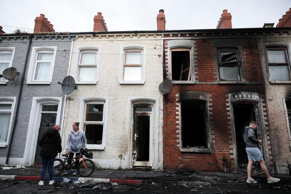 People inspect damage to a residential neighborhood after anti-immigrant protests and riots.