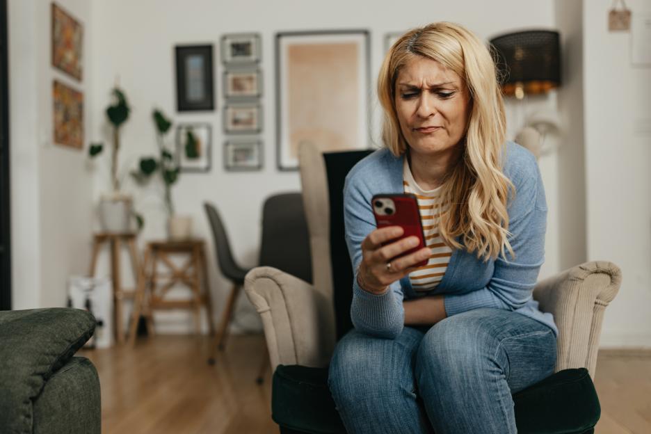 Woman with a distressed expression looking at her smartphone.