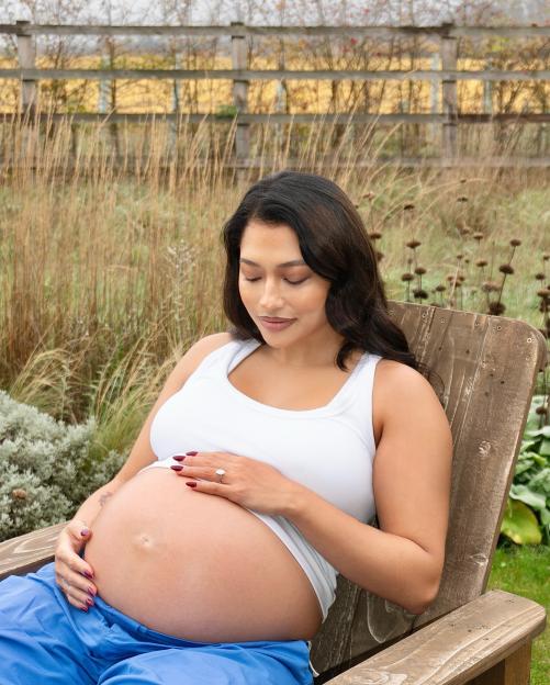 Vanessa White sitting in a chair, cradling her pregnant belly.