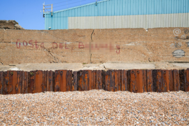 Rusty sea wall with graffiti.
