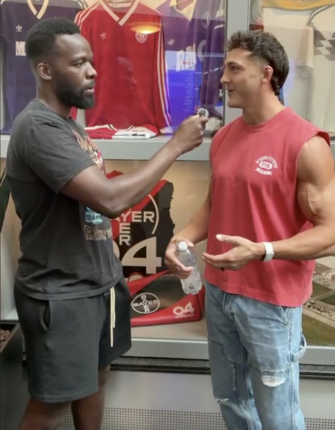 A man holding a microphone interviewing another man.