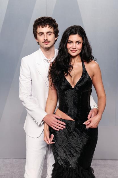 Timothée Chalamet and Kylie Jenner posing together, with Chalamet's arms around Jenner.