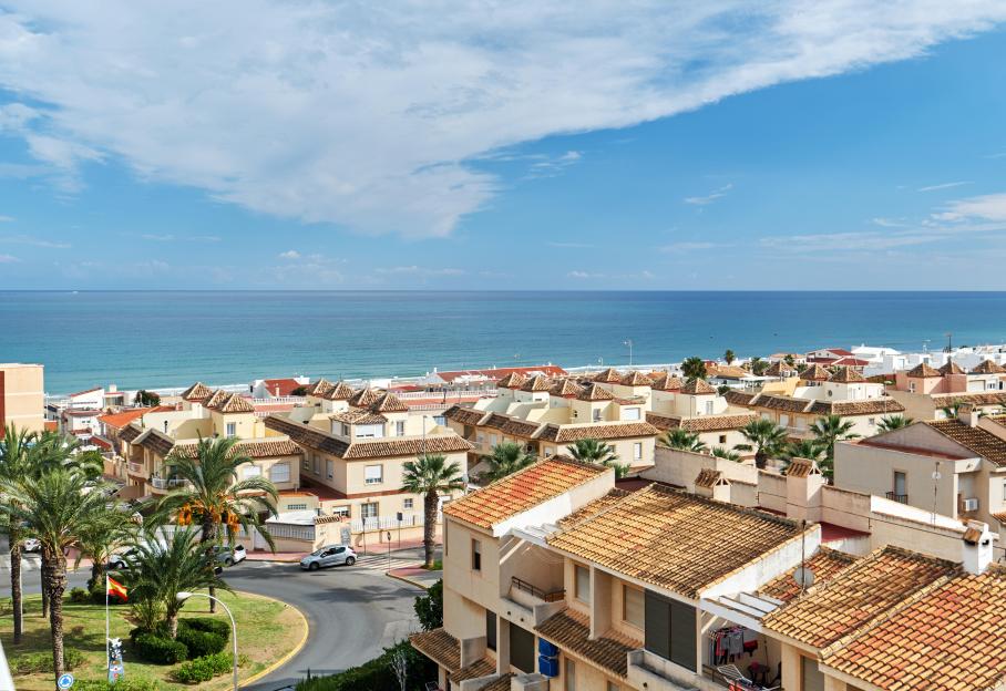 Seaside of Guardamar del Segura city. Coastal residential buildings, houses, architecture of resort town. Rooftops, urban scene. Mediterranean sea and