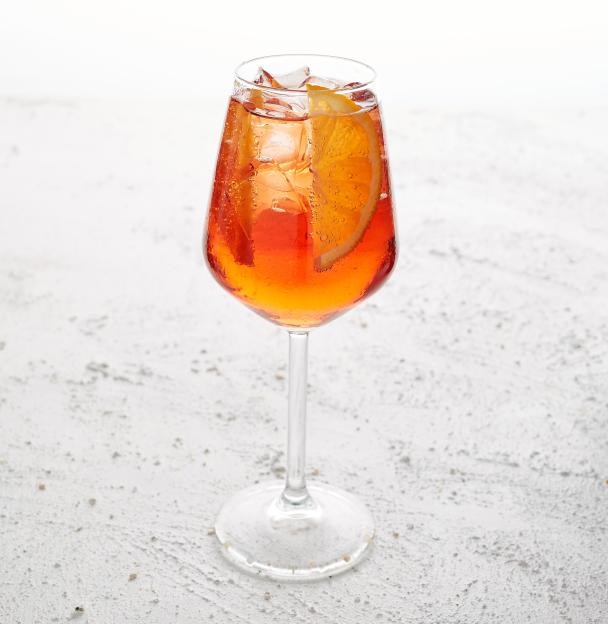 Alcoholic Aperol Spritz cocktail with orange slice and ice in a wine glass.