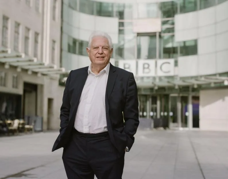 John Simpson stands in front of the BBC building.