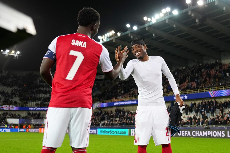 Arsenal teammates Noni Madueke and Bukayo Saka high-five on the field.
