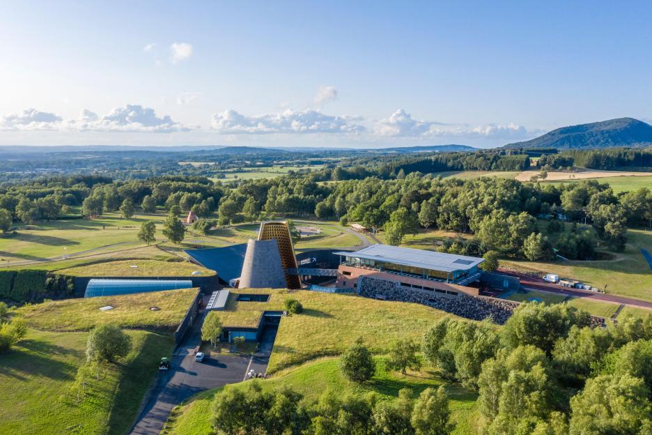 Aerial view of Vulcania in France's Volcans d'Auvergne Regional Natural Park, with buildings seamlessly integrated into the green landscape.