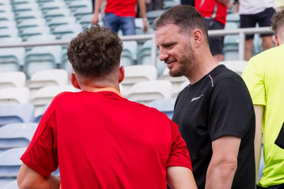 A man in a black shirt smiling at a person in a red shirt.