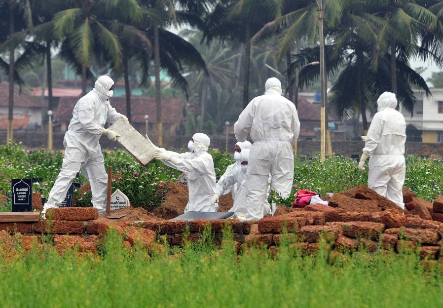 Doctors and relatives wearing protective gear dig a grave to bury the body of a victim, who lost his battle against the brain-damaging Nipah virus, during his funeral at a burial ground in Kozhikode