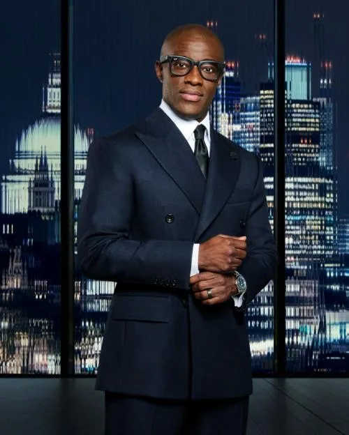 Tim Campbell MBE in a dark suit against a city backdrop.