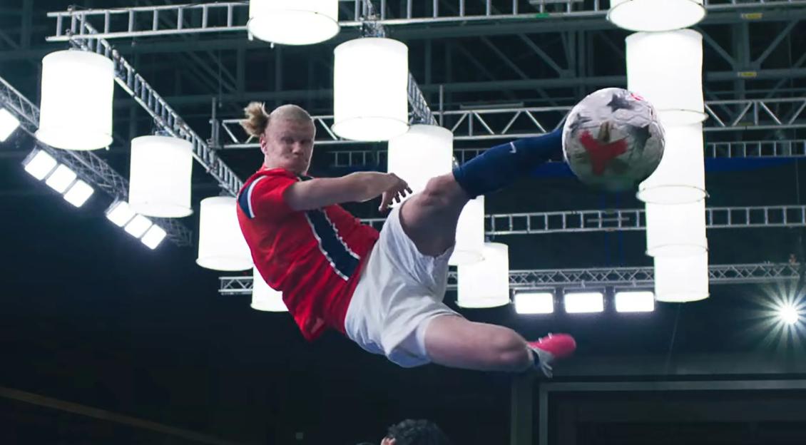 Erling Haaland in mid-air kicking a soccer ball.