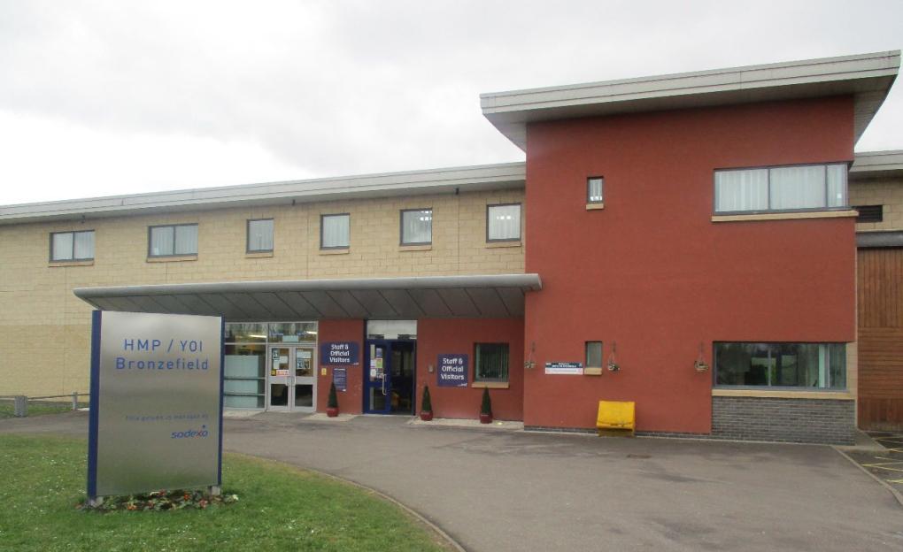 HMP & YOI Bronzefield building entrance with a sign reading "HMP / YOI Bronzefield, this prison is managed by Sodexo".