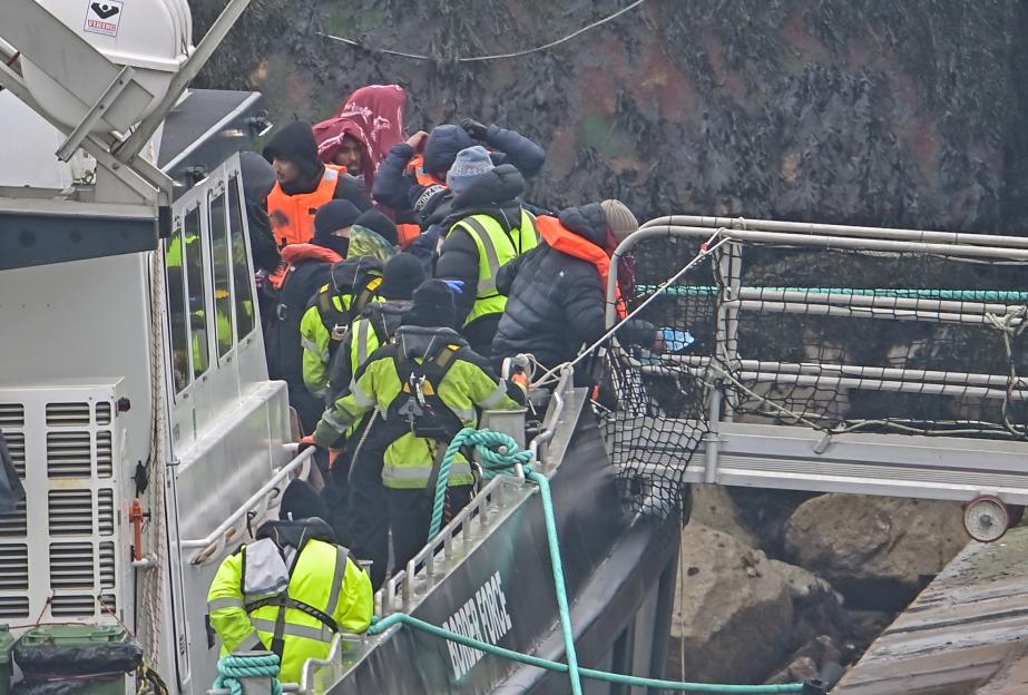 Migrants being escorted ashore from a Border Force vessel at Ramsgate Docks.