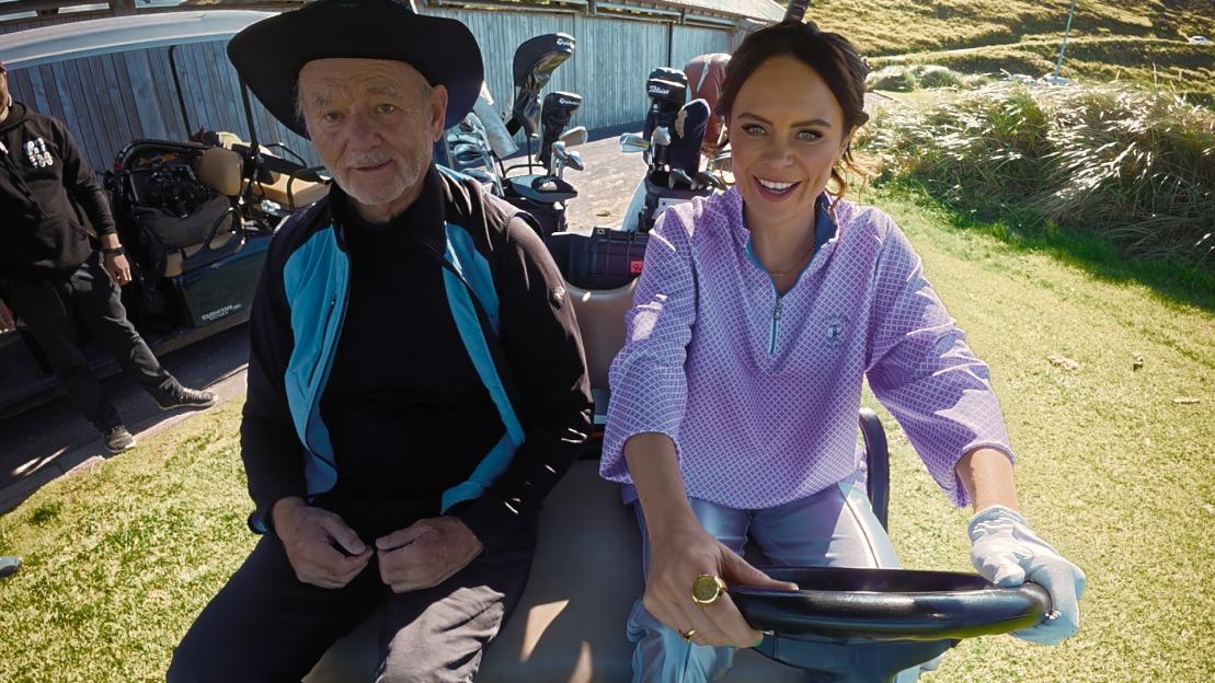 Bill Murray and Joanne McNally in a golf cart.