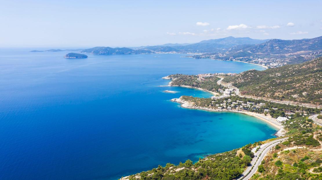 Aerial view of the Kavala seascape in Greece, with mountains, beaches, and a coastal road.