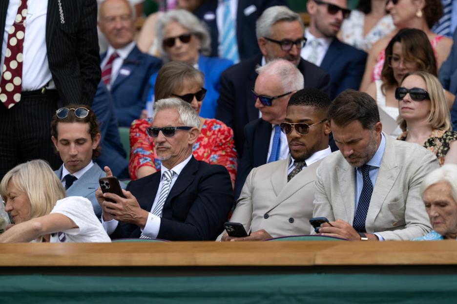 Boxing promoter Eddie Hearn and professional boxer Anthony Joshua look at their phones.