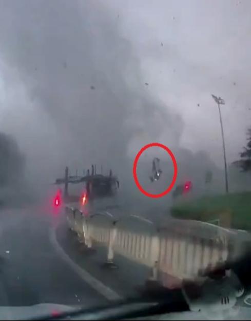 A person is seen flying through the air after being caught in a tornado, circled in red.