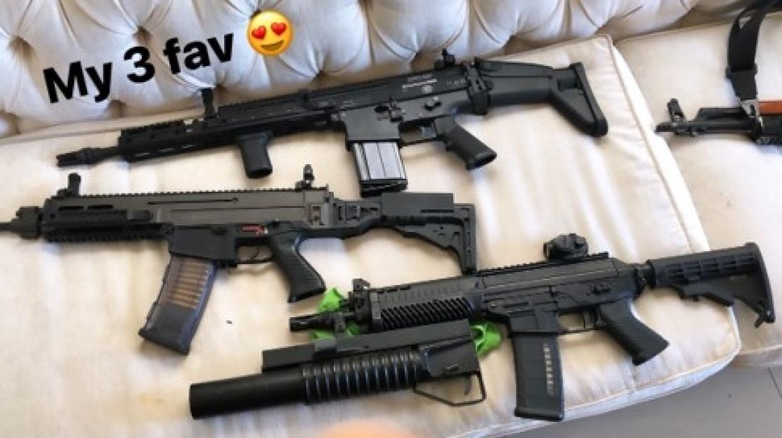 Three firearms, including a rifle, laid on a white couch.
