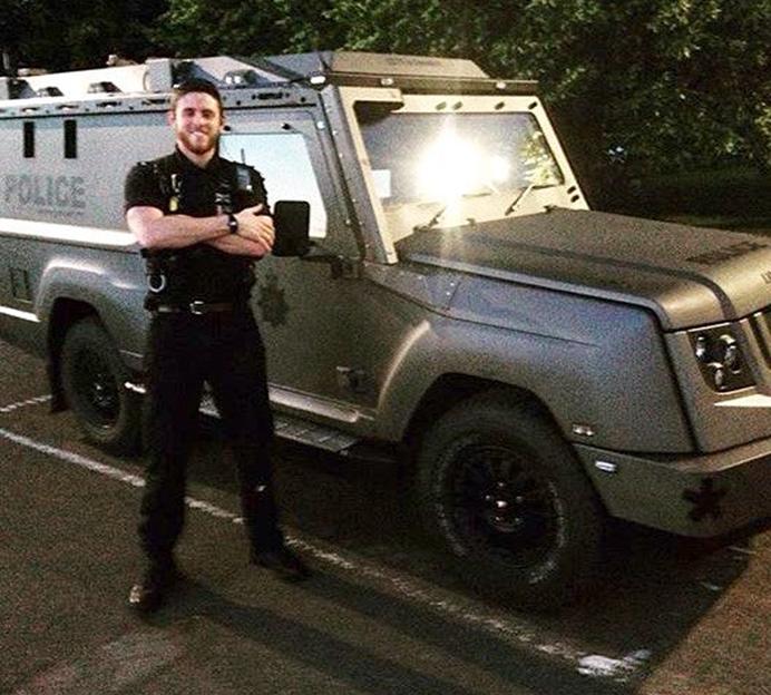 PC Andrew Harper standing in front of a police armored vehicle.